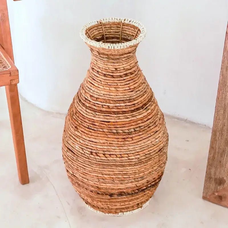 Große Bodenvase Tumbak aus Naturfasern vor weißer Wand, bauchige Form.