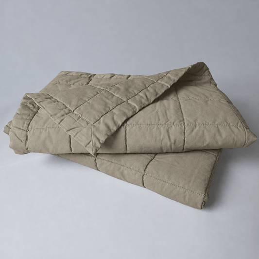 Tagesdecke Mira von Evelyn Kahle in Khaki, gefaltet mit quadratischer Steppung und umgeschlagener Ecke
