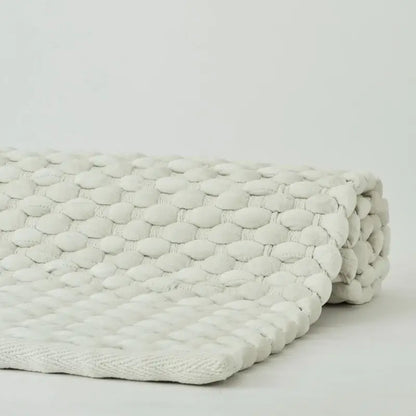 Badteppich Maks von Aquanova in Pearl Cremeweiß, Detailaufnahme der noppenartigen Struktur und eingefassten Kante

