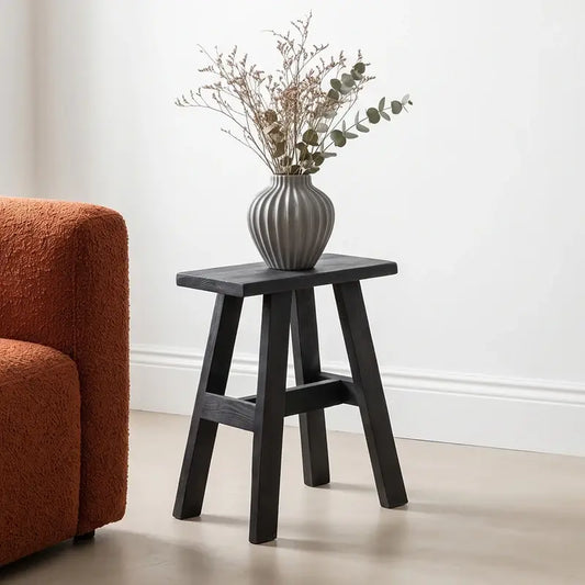 Schwarzer Blumenhocker Fabric von Raw Materials aus Holz – kleiner Beistellhocker als dekorative Ablage für Pflanzen und Wohnaccessoires