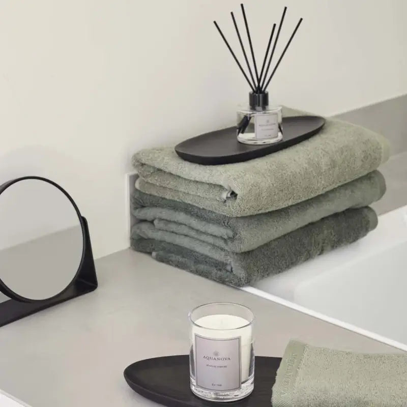 Gemütliches Spa-Badezimmer mit Duftkerze, weichen Handtüchern und stimmungsvoller Beleuchtung für eine entspannte Wellness-Atmosphäre.