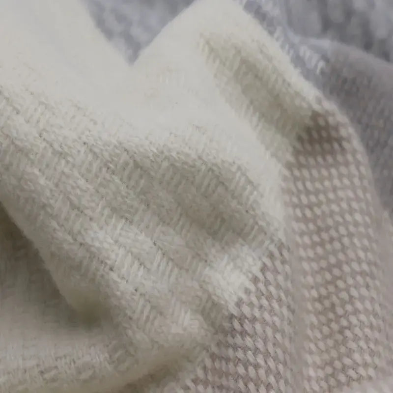 Nahaufnahme der Merinowolle Kuscheldecke mit Zierstich-Einfassung und mehrfarbigem Gewebe