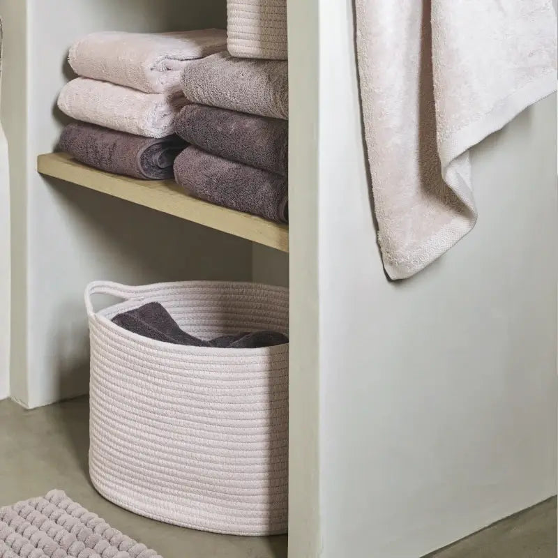 Natürliches Badezimmer in Beige und Weiß mit Holzelementen, Handtüchern und Wäschekorb für eine warme und harmonische Wohlfühlatmosphäre.