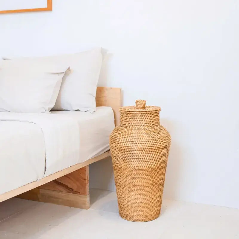 Rattan-Bodenvase Kidung mit passendem Deckel als dekoratives Aufbewahrungselement im Schlafzimmer.